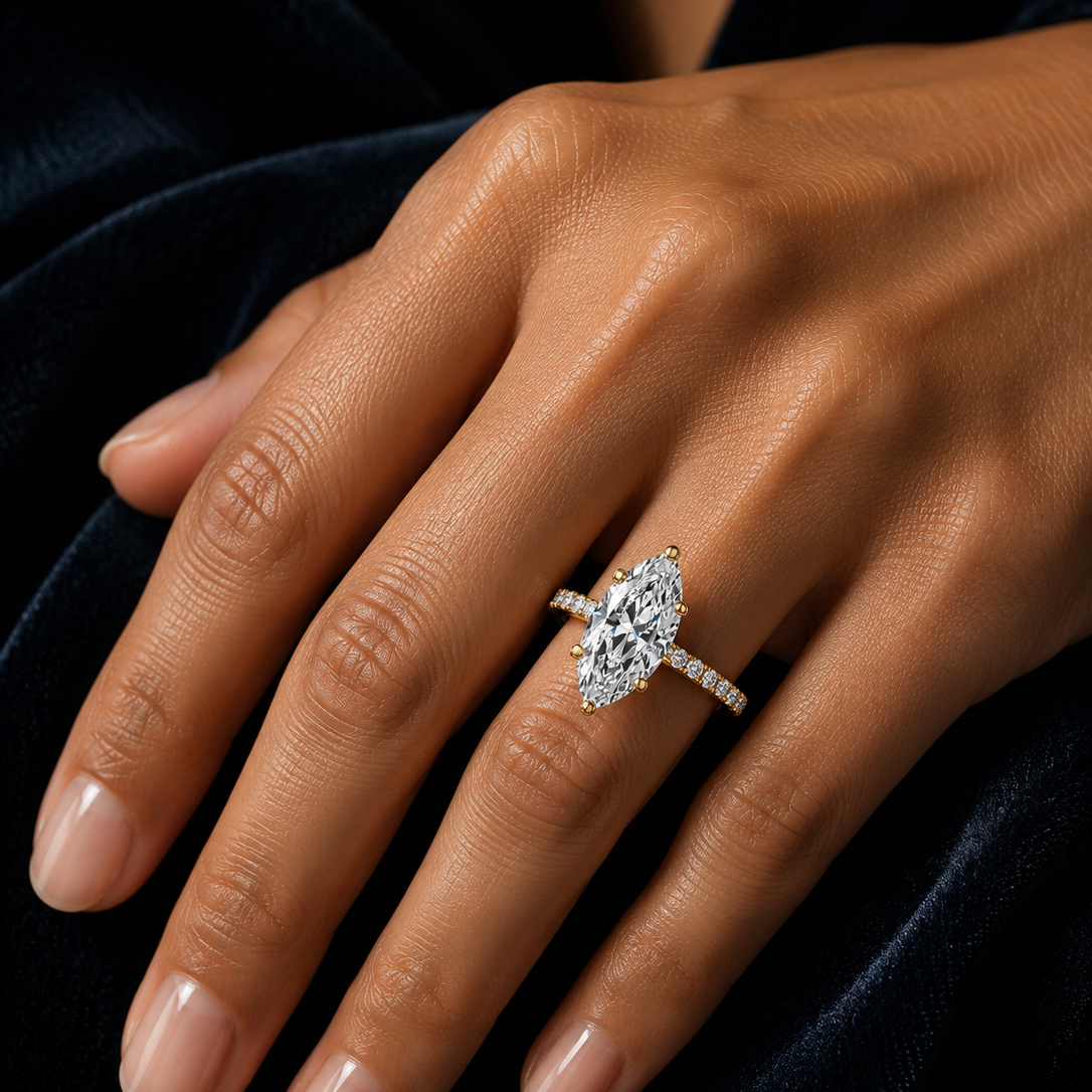 Marquise cut solitaire engagement ring with pavé diamond band in yellow gold, featuring a brilliant moissanite or lab-grown diamond center stone, handcrafted by Frigus Jewelry.