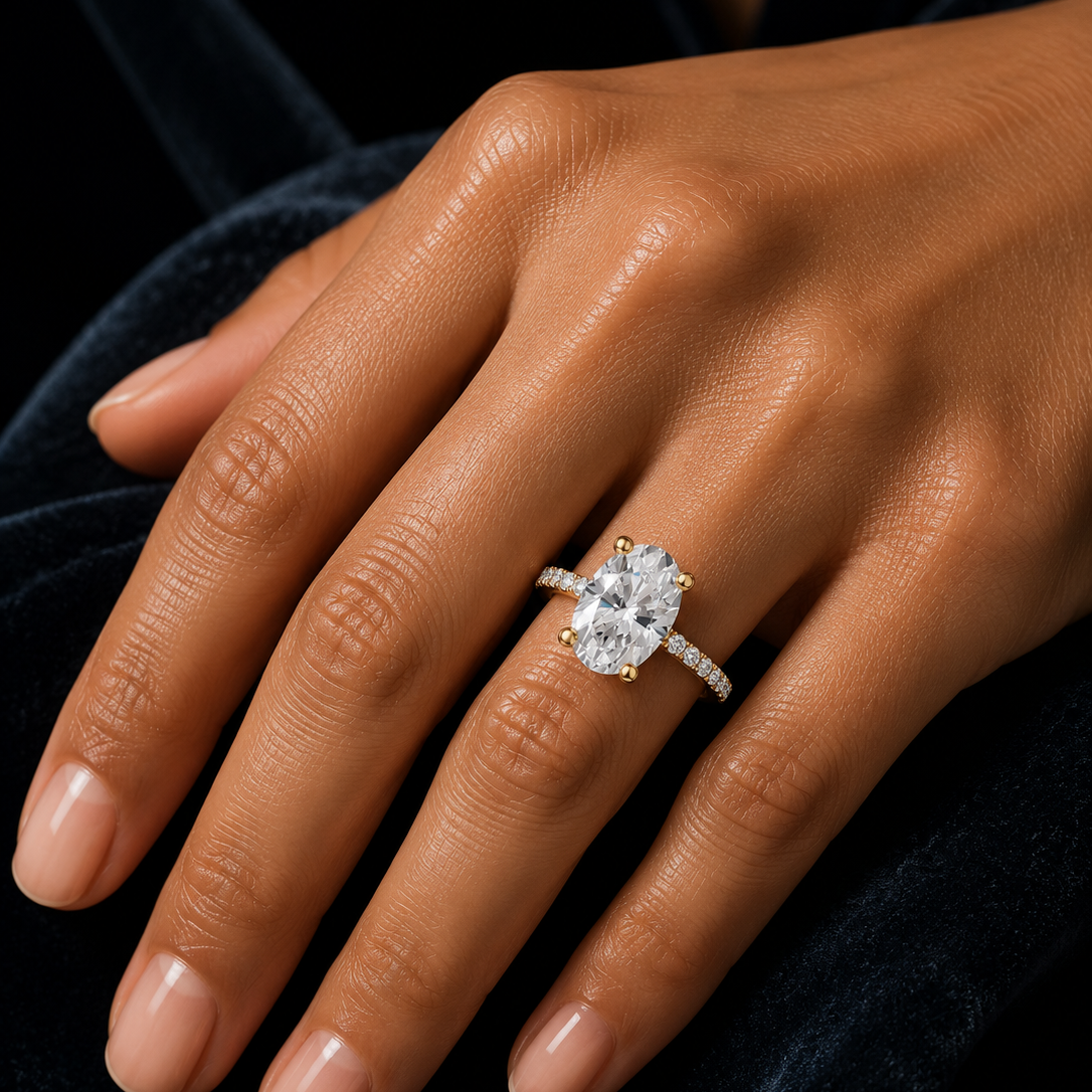 Oval cut solitaire engagement ring with pavé diamond band in yellow gold, featuring a brilliant moissanite or lab-grown diamond center stone, handcrafted by Frigus Jewelry.